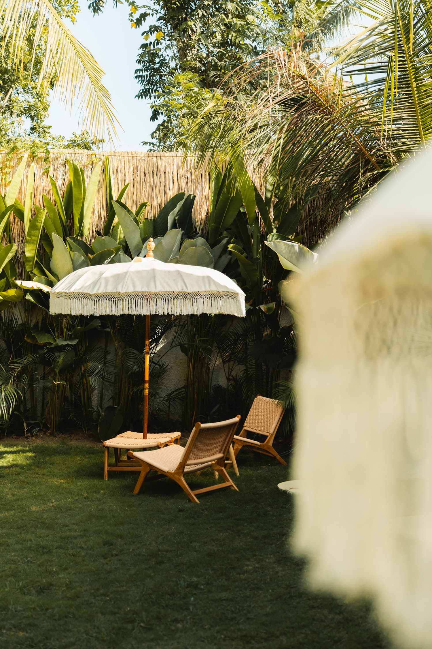 White fringed parasol and wooden loungers in the garden
