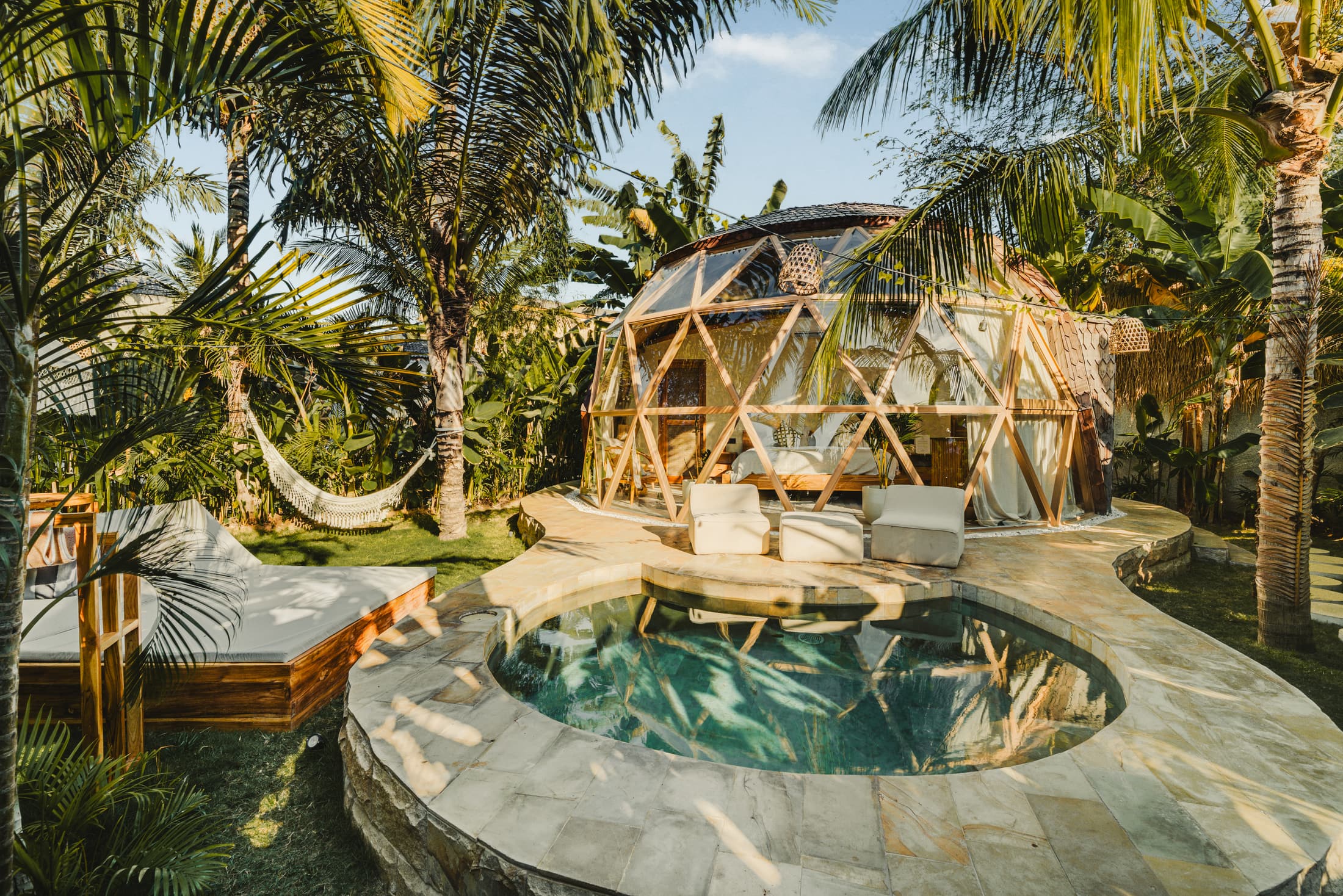 A dome and its round plunge pool among palm trees